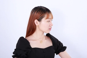 Detail shot of model wearing a textured gold round necklace and matching earrings set