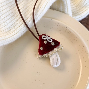 Close-up of handmade red mushroom pendant with velvet texture, pearls, and lace detail
