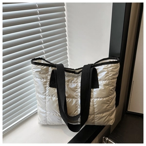 Close-up of silver quilted tote bag with space cotton texture and black straps