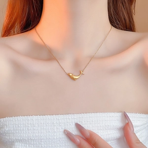 Close-up of golden whale pendant necklace with zircon stone on elegant female model