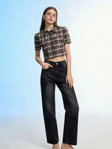 Dettaglio macro di jeans a vita alta e gamba dritta con camicia a quadri vintage
