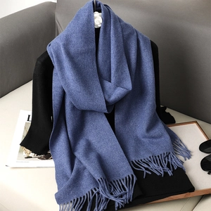 Dettaglio sciarpa blu in finto cashmere con nappe su vassoio di legno per inverno