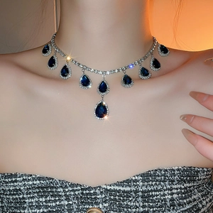 Dettaglio di una collana con pietre blu a goccia e piccoli strass indossata da un modello