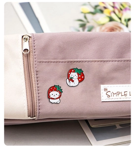 Detailed close-up of cute strawberry cat enamel pins on a purple canvas bag surface