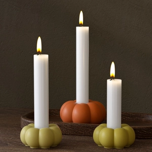 Detailed view of Halloween pumpkin candle holders with white pillar candles on a wooden tray