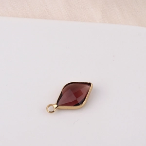 Detail of a rhombus pendant with dark red faceted crystal and gold plated frame for DIY