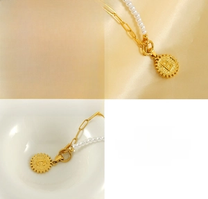 Detail view of gold stainless steel paperclip chain necklace with pearls and OT clasp