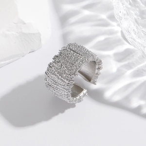 Detail of silver wide band ring with woven texture on a white stone background