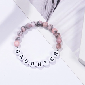 Detail of 8mm pink zebra stone beads and white DAUGHTER letter beads on a stretch bracelet