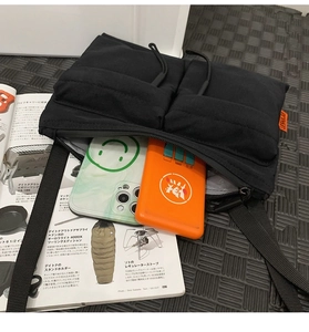Detail of black nylon messenger bag with drawstring showing capacity for phone and power bank