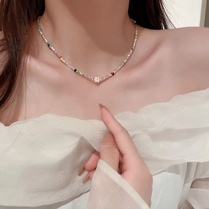 Collier ras du cou perles colorées et fleur avec accents argentés sur le cou du mannequin