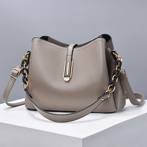 Taupe pebbled leather handbag with gold-black chain and adjustable strap on geometric platform