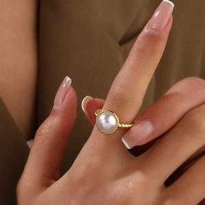 Detail of twisted 18k gold plated ring with a large white pearl on a woman's hand