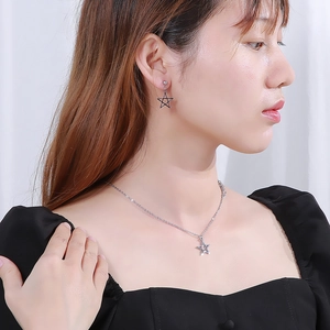 Detailed view of model wearing a silver hollow star necklace and matching stud earrings