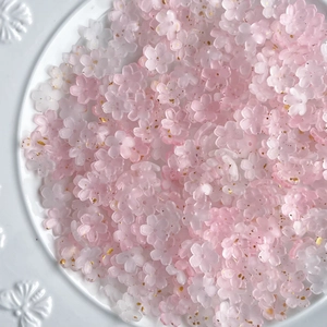 Close-up of pink and white resin flower beads with gold glitter on a white plate