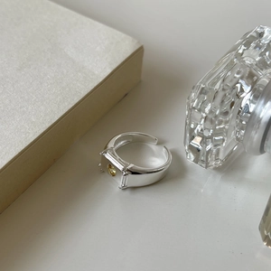 Detailed view of an irregular textured silver ring featuring a yellow square gemstone