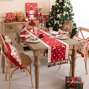 Christmas table runner with reindeer and snowflake patterns and decorative red tassels
