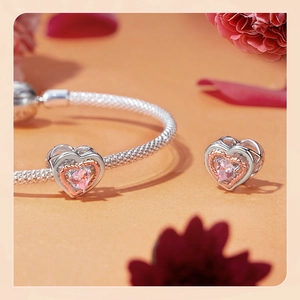 Close-up of S925 silver charm bracelet featuring pink heart crystals and rose gold borders