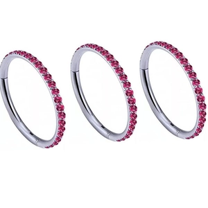 Three G23 titanium nose rings with silver hoops and pink crystals on a white background