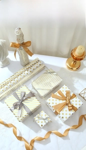 Close-up of white and gold gift wrap with stripe and dot patterns and satin ribbons