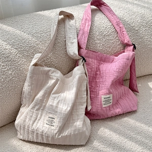 Detailed texture of pleated canvas tote bags in cream and pink on a white sofa