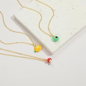 Colorful enamel mushroom and cartoon monster pendant necklaces on stone display