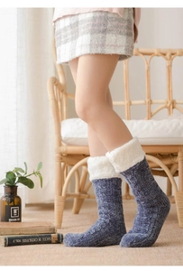 Close-up of blue cable knit winter socks with white plush cuffs in a cozy home setting
