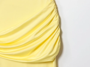 Detail of bright yellow tiered backless maxi dress showing pleated fabric texture