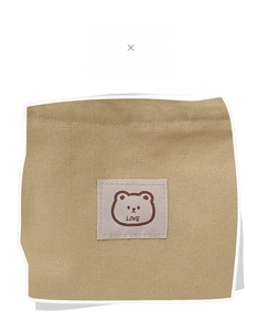 Detail of high-density khaki canvas material featuring a cute embroidered cartoon bear label