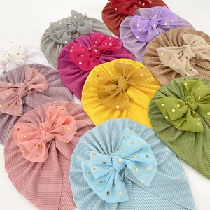 Detail of colorful ribbed baby turbans featuring large gold-dotted chiffon bows