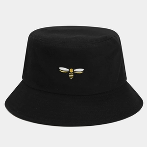 Close-up of black cotton bucket hat featuring detailed yellow bee embroidery on the front