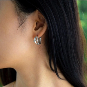 Minimalist 925 sterling silver woven hoop earrings on female model with soft lighting