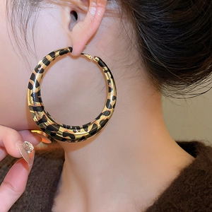 Close-up of stylish leopard print hoop earrings with a gold metallic finish on model