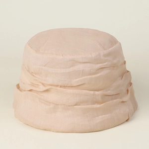 Détail d'un chapeau cloche en ramie beige montrant les plis superposés et le tissu aéré