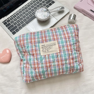 Close-up of quilted orange and purple plaid cosmetic bag with stitched label detail