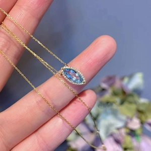 Détail macro du pendentif marquise aigue-marine avec halo de diamants sur chaîne dorée