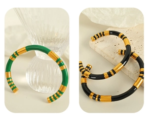 Detail view of retro stainless steel gold bangles with green and black enamel inlay inserts