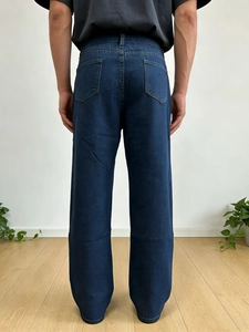 Detailed back view of men's relaxed-fit washed denim jeans in dark blue with pocket texture