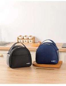 Detail of insulated lunch bags with dual zippers and side mesh pockets on a wooden table