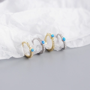 Macro detail of gold and silver S925 sterling silver huggie hoops with blue opal stones