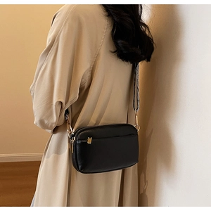 Detail of black PU leather crossbody bag with a stylish woven texture shoulder strap