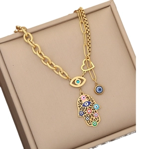 Golden stainless steel Hamsa necklace with colorful evil eye charms on a jewelry box