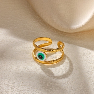 Detail of golden adjustable evil eye ring with hammered texture and green enamel on silk
