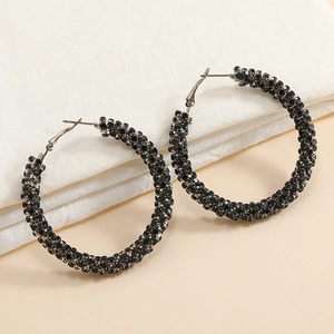 Close-up of oversized circular earrings featuring micro-set black rhinestones