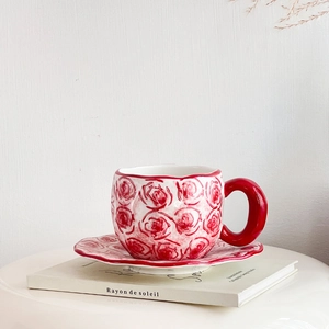 Detail of white ceramic coffee cup and saucer set with hand-painted red roses