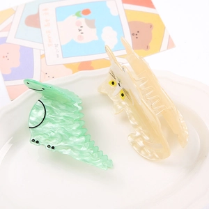 Cute acetate hair claws featuring pastel green dinosaur and beige cat shapes in a tray