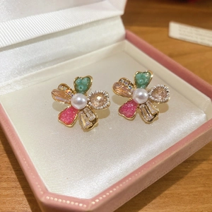 Macro view of crystal flower stud earrings with green beads and pink resin petals