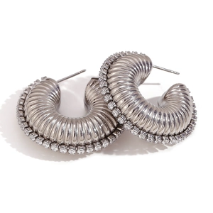 Detailed view of silver C-shaped shrimp earrings with textured metal and zircon inlay