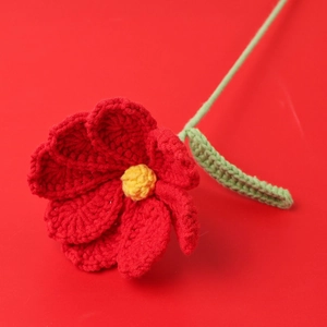 Handmade crochet flower in vibrant red petals and yellow core on a matching red background