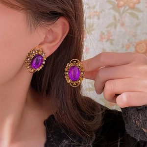 Detail of vintage oval purple gem earrings with gold filigree and tiny pearls on model